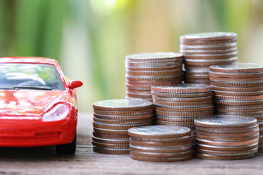 Image of a stack of coins next to a red toy car.